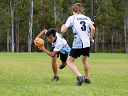 Two boys playing touch football on field.